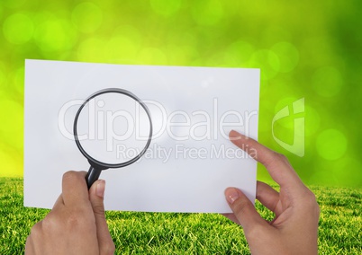 Holding Magnifying glass over paper with grass