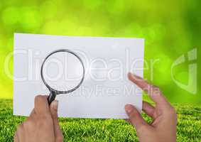 Holding Magnifying glass over paper with grass