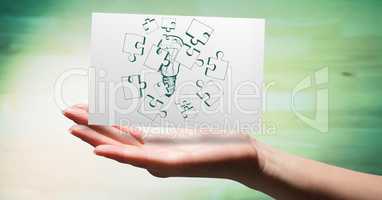 Hand with card showing green jigsaw doodle against blurry green wood panel