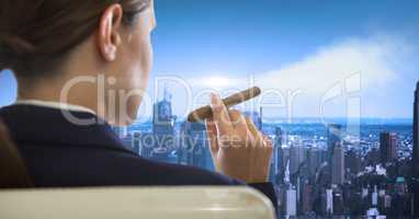 Rear view of businesswoman sitting in chair smoking looking at cityscape