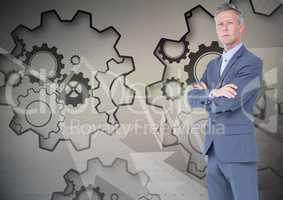 Digital composite image of businessman with arms crossed standing against gears