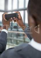 Businessman holding phone by windows