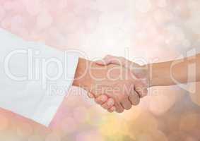 Hands shaking with sparkling light bokeh background