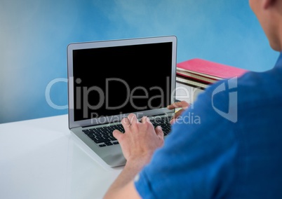 Man using laptop with blue background and desk