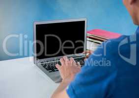 Man using laptop with blue background and desk
