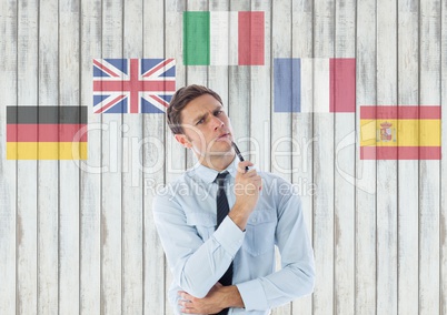 main language flags around young businessman thinking. Wood background