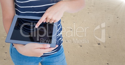 Woman mid section with tablet against sand and flare