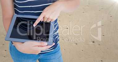 Woman mid section with tablet against sand and flare