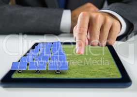 solar panels on grass on tablet with businessman hand