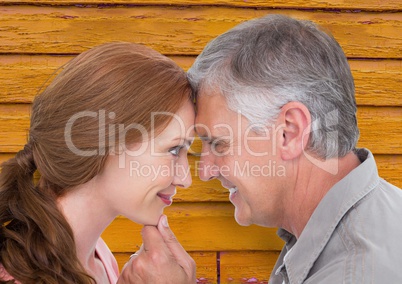 couple looking each other with yellow wood background