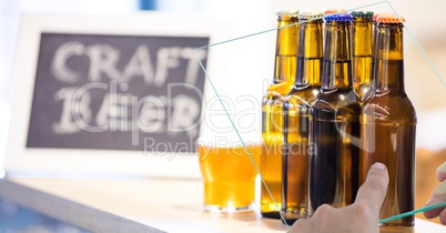 Hand taking picture of beer bottles through transparent device at bar