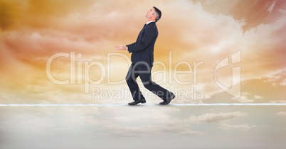 Digital composite image of businessman balancing on rope
