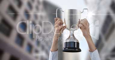Cropped image of hands holding trophy against buildings