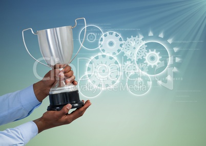 Digital composite image of hand holding trophy against gears