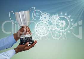 Digital composite image of hand holding trophy against gears