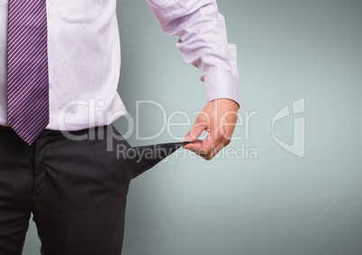 Midsection of businessman showing empty pocket standing against green background