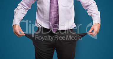 Midsection of businessman showing empty pockets against blue background