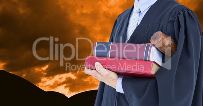 Midsection of lawyer holding books and gavel against dramatic sky