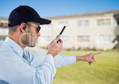 Security guard holding walkie talkie and gesturing while standing on field