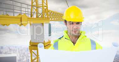 Male architect looking at blueprint while standing by crane against sky