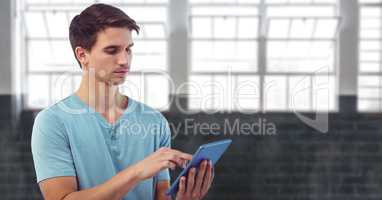 Young man using digital tablet while standing against window