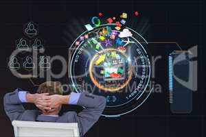 Business man seated on a chair is watching digital image against black background