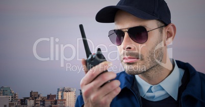 Security guard with walkie talkie against skyline and purple sky