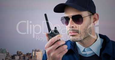 Security guard with walkie talkie against skyline and purple sky