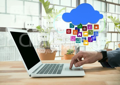 Businessman using laptop with apps icons by bright windows with plants