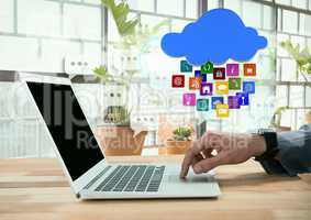 Businessman using laptop with apps icons by bright windows with plants
