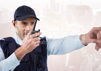 Security guard with walkie talkie pointing against faded skyline