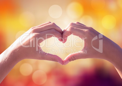 Hands making heart shape with sparkling light bokeh background