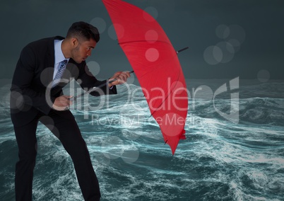 Business man behind umbrella against stormy sea with bokeh