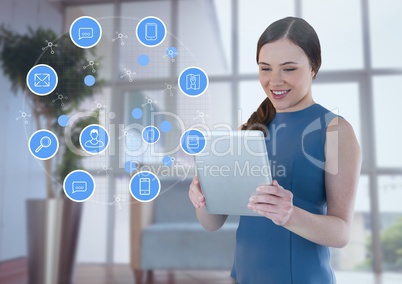 Businesswoman holding tablet with apps icons in office by window