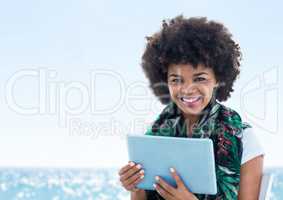 Woman with tablet against blurry water on sunny day