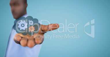 Business man with blue cloud and gear graphic in outstretched hand against blue background