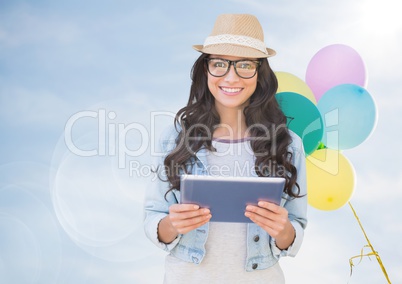 Trendy woman with tablet against sunny sky and balloons with flare