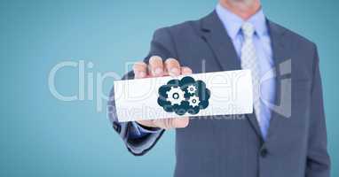 Business man mid section with card showing blue cloud and gear graphic against blue background
