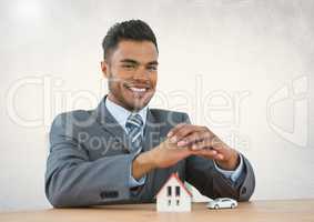Man with protective hands over small house