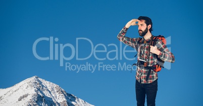 Happy rambler looking far away in front of snow-covered mountains with blue sky