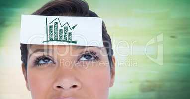 Close up of woman with card on head showing green graph against blurry green wood panel