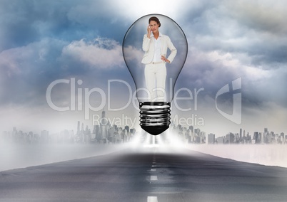 Digital composite image of businesswoman standing in bulb on road against cityscape