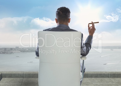 Rear view of businessman smoking cigar while looking at sea