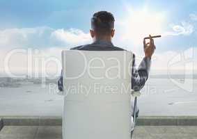 Rear view of businessman smoking cigar while looking at sea