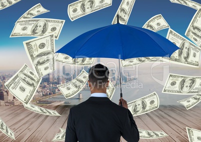Digital composite image of businessman holding blue umbrella while standing amidst currencies