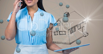 Midsection of woman talking on mobile phone while holding digital tablet with house symbol and conne