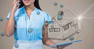 Midsection of woman talking on mobile phone while holding digital tablet with house symbol and conne