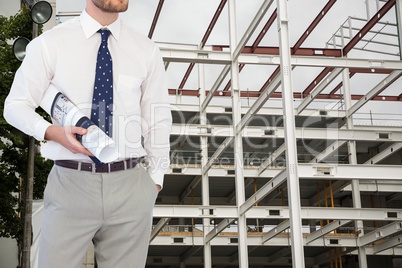 Architect holding a plan against a construction