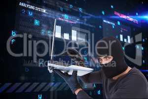 Cyber criminal holding a laptop and wearing a hood against matrix background