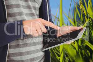 Model touching tablet computer screen against nature background